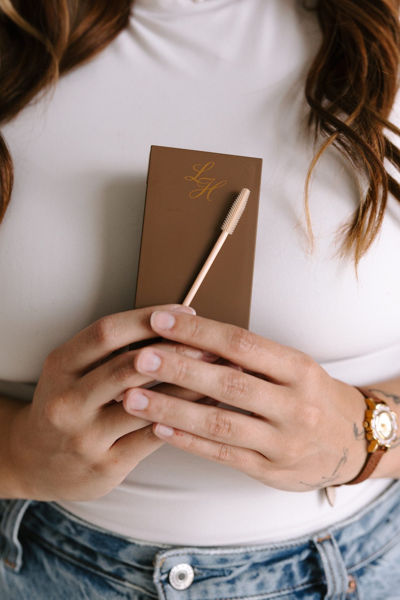 A client holding a personalized lash aftercare card and spoolie brush